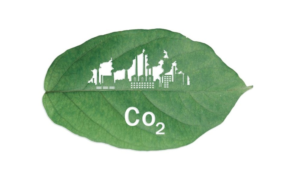 Zielony liść z graficzną sylwetą zakładów przemysłowych i symbolem CO₂, symbolizujący wpływ działalności człowieka na środowisko.